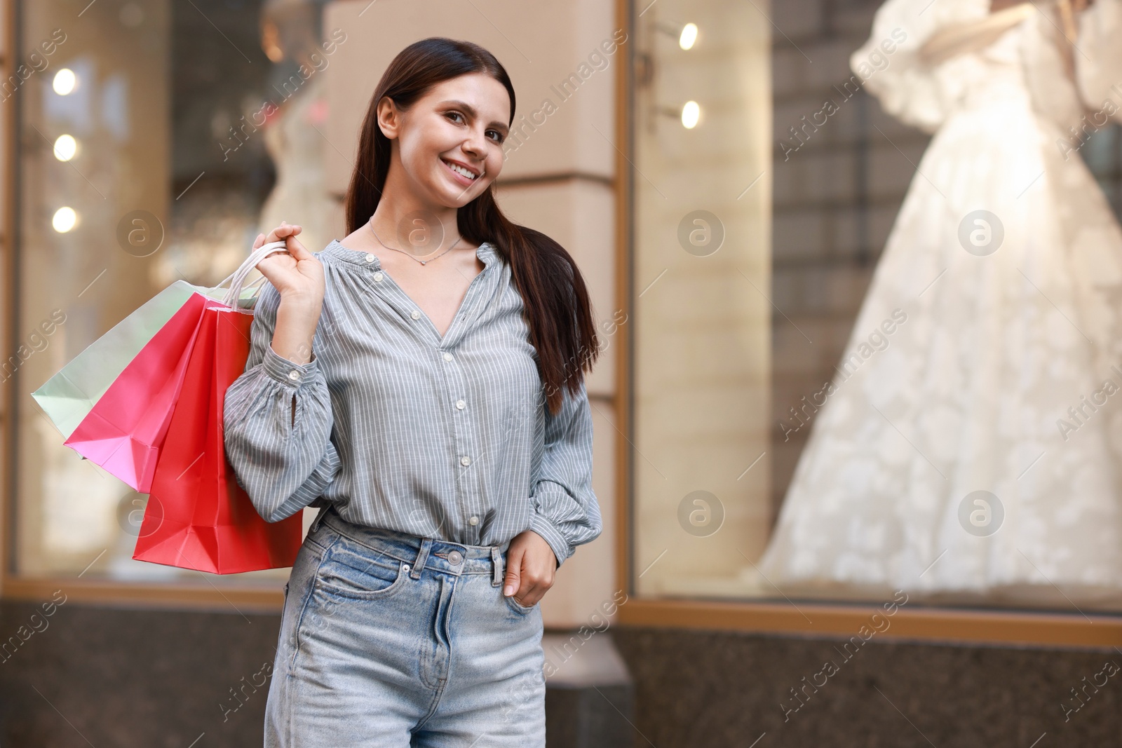 Photo of Happy woman with colorful shopping bags outdoors, space for text