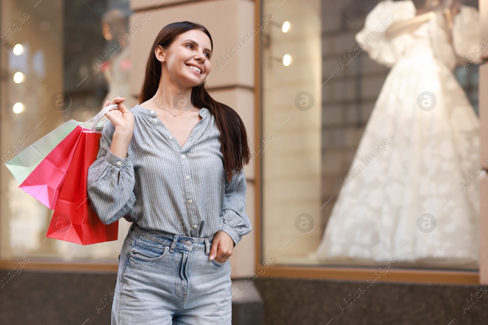 Photo of Happy woman with colorful shopping bags outdoors, space for text