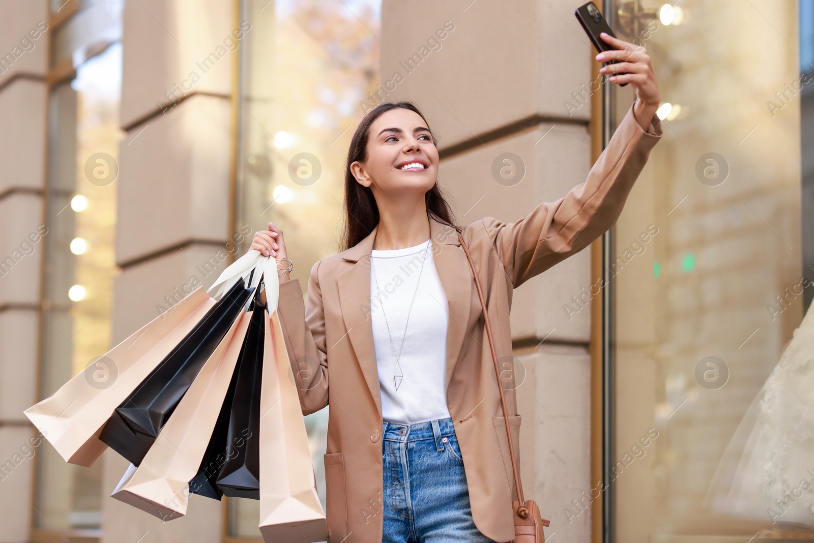 Photo of Happy woman with many shopping bags taking selfie outdoors