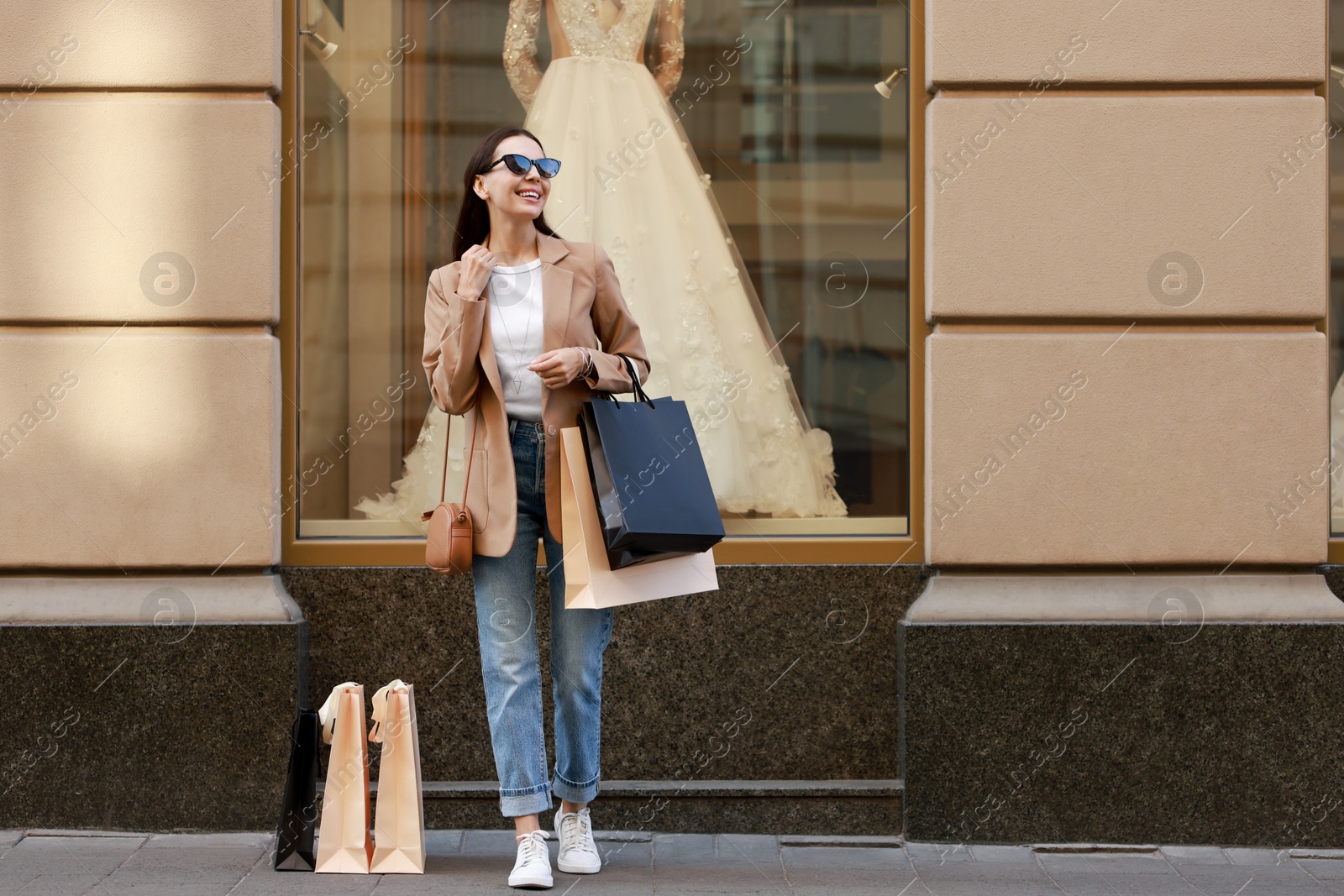 Photo of Happy woman with many shopping bags outdoors