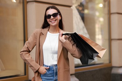 Happy woman with many shopping bags outdoors