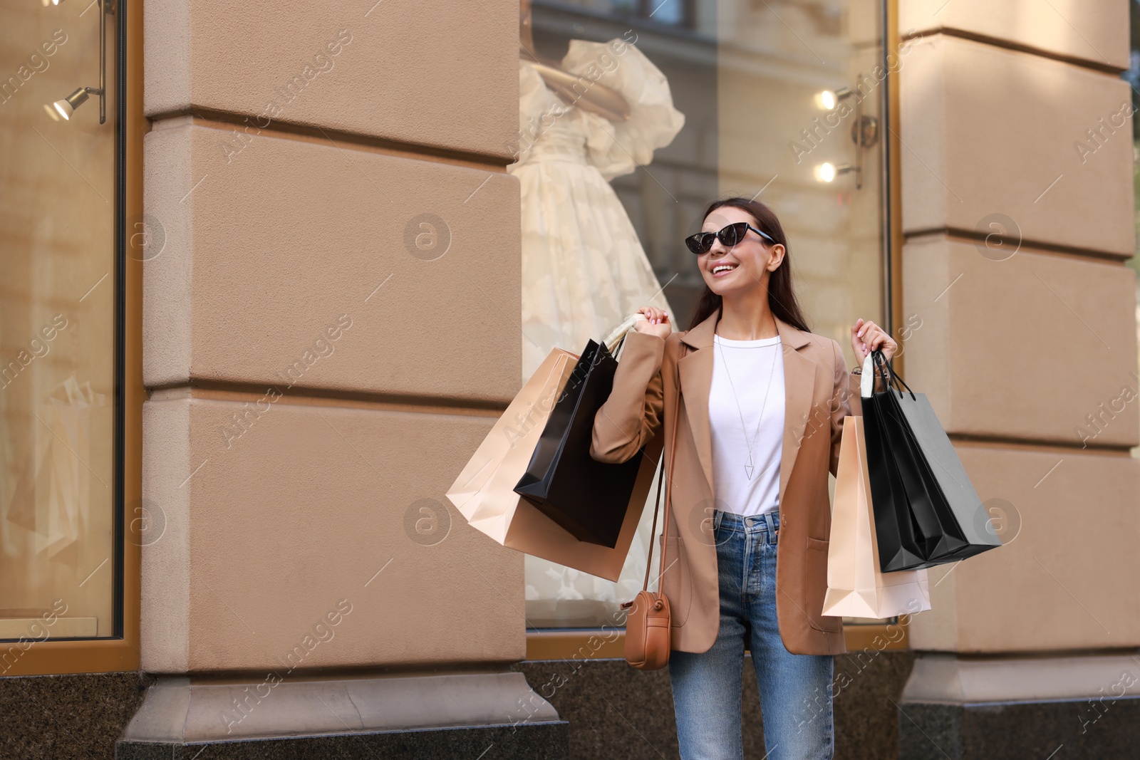 Photo of Happy woman with many shopping bags outdoors