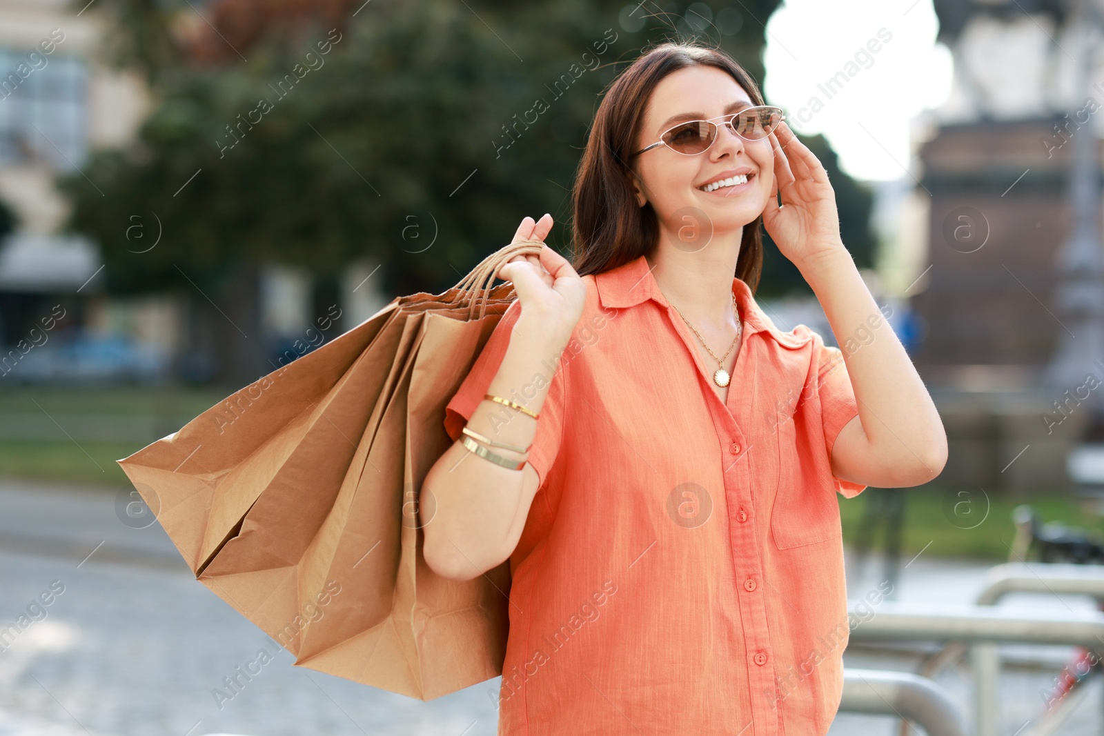 Photo of Happy woman with many shopping bags outdoors