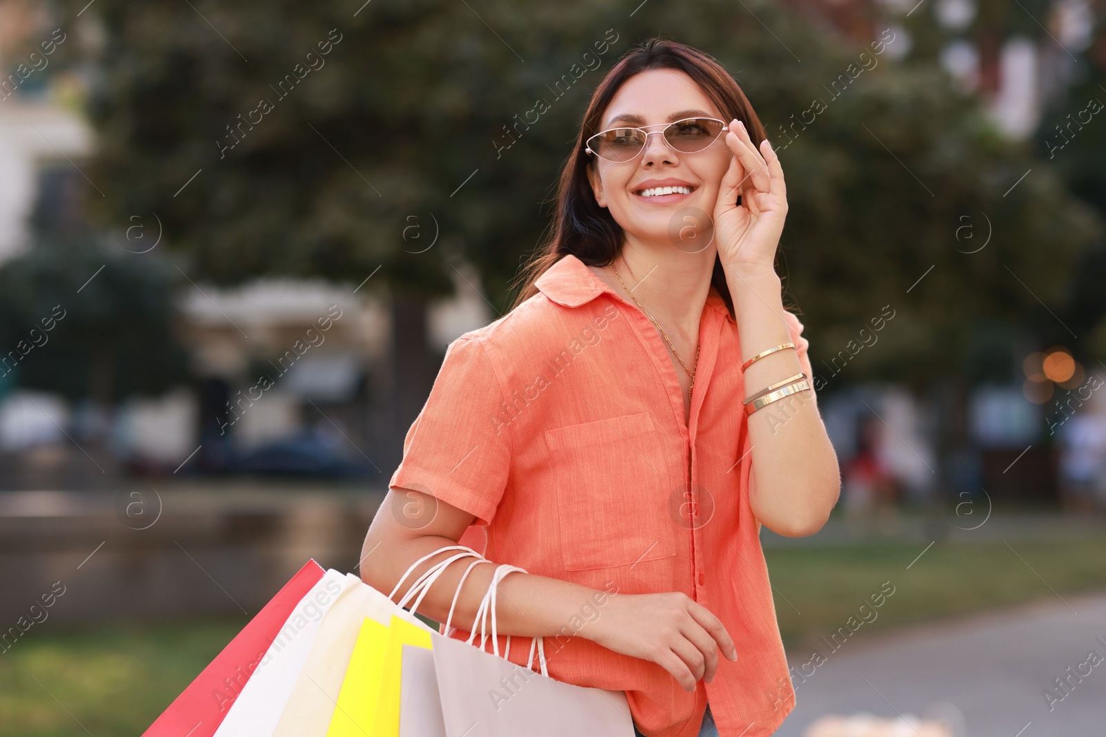 Photo of Happy woman with colorful shopping bags outdoors