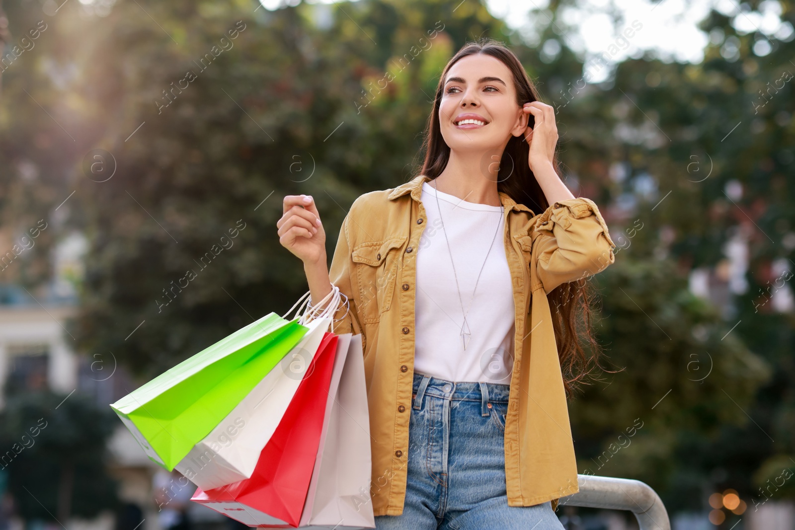 Photo of Happy woman with colorful shopping bags outdoors