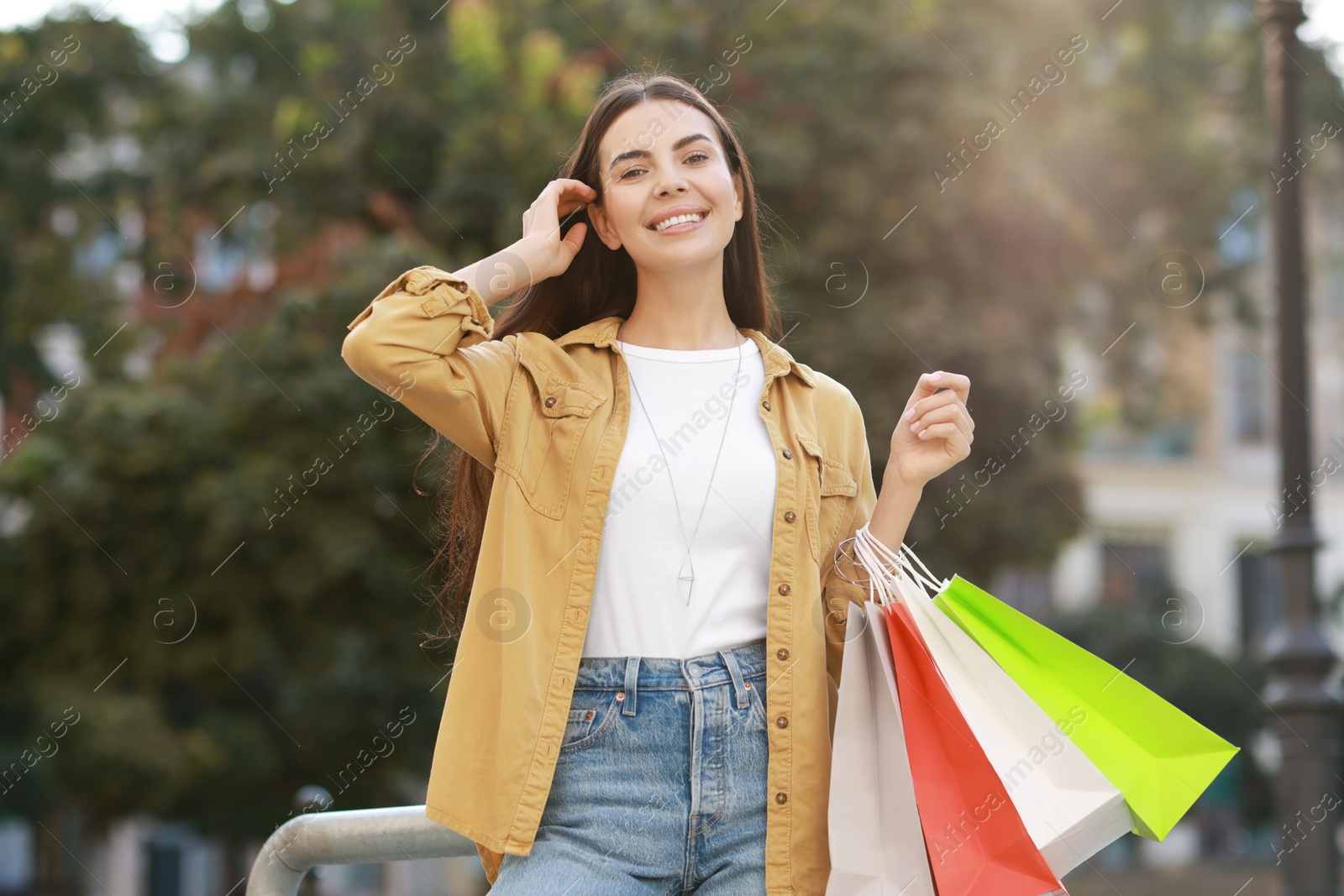 Photo of Happy woman with colorful shopping bags outdoors