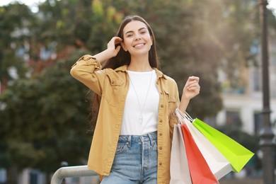 Happy woman with colorful shopping bags outdoors