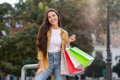 Happy woman with colorful shopping bags outdoors