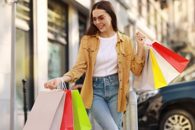 Happy woman with colorful shopping bags outdoors