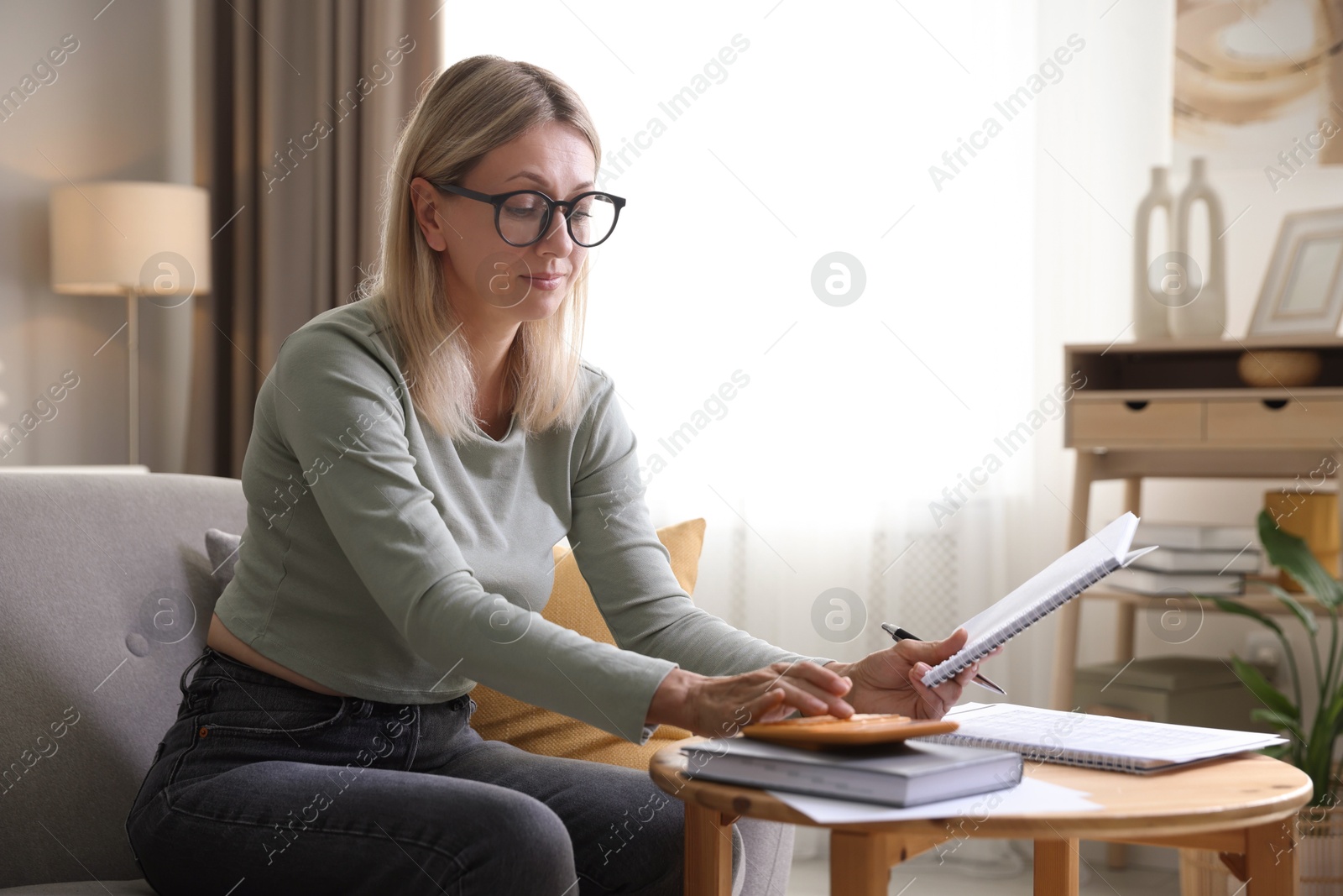 Photo of Budget planning. Woman using calculator while working with accounting document at table indoors