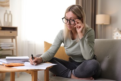 Photo of Budget planning. Woman working with accounting documents at table indoors