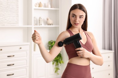 Woman using percussive massager to relieve bicep at home