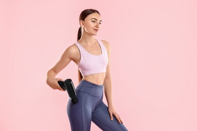 Woman using percussive massager to relax hip muscles on pink background