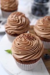 Photo of Tasty cupcakes with chocolate cream and blueberries on table, closeup