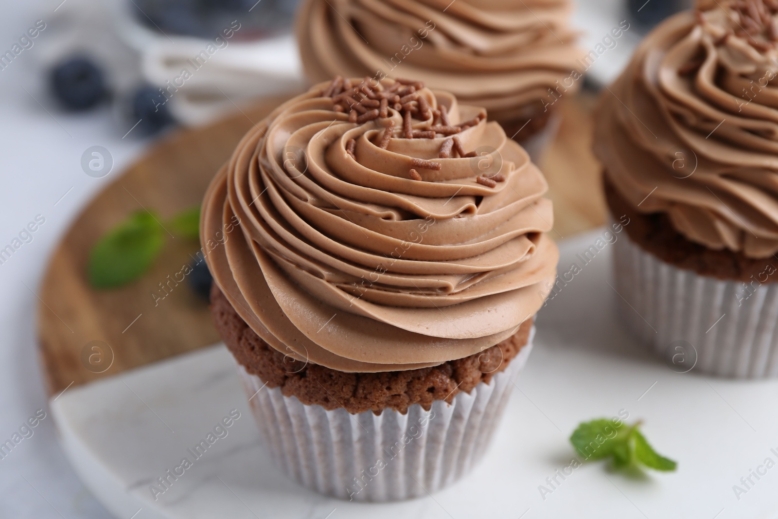 Photo of Tasty cupcakes with chocolate cream on table, closeup