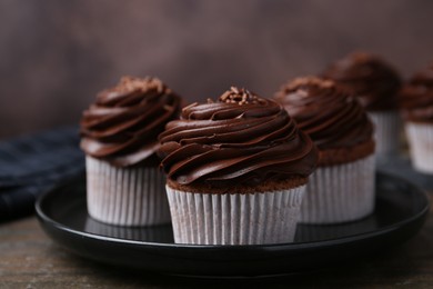 Photo of Tasty cupcakes with chocolate cream on wooden table, closeup