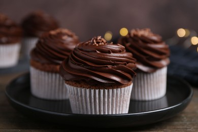 Photo of Tasty cupcakes with chocolate cream on wooden table, closeup