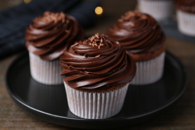 Photo of Tasty cupcakes with chocolate cream on wooden table, closeup