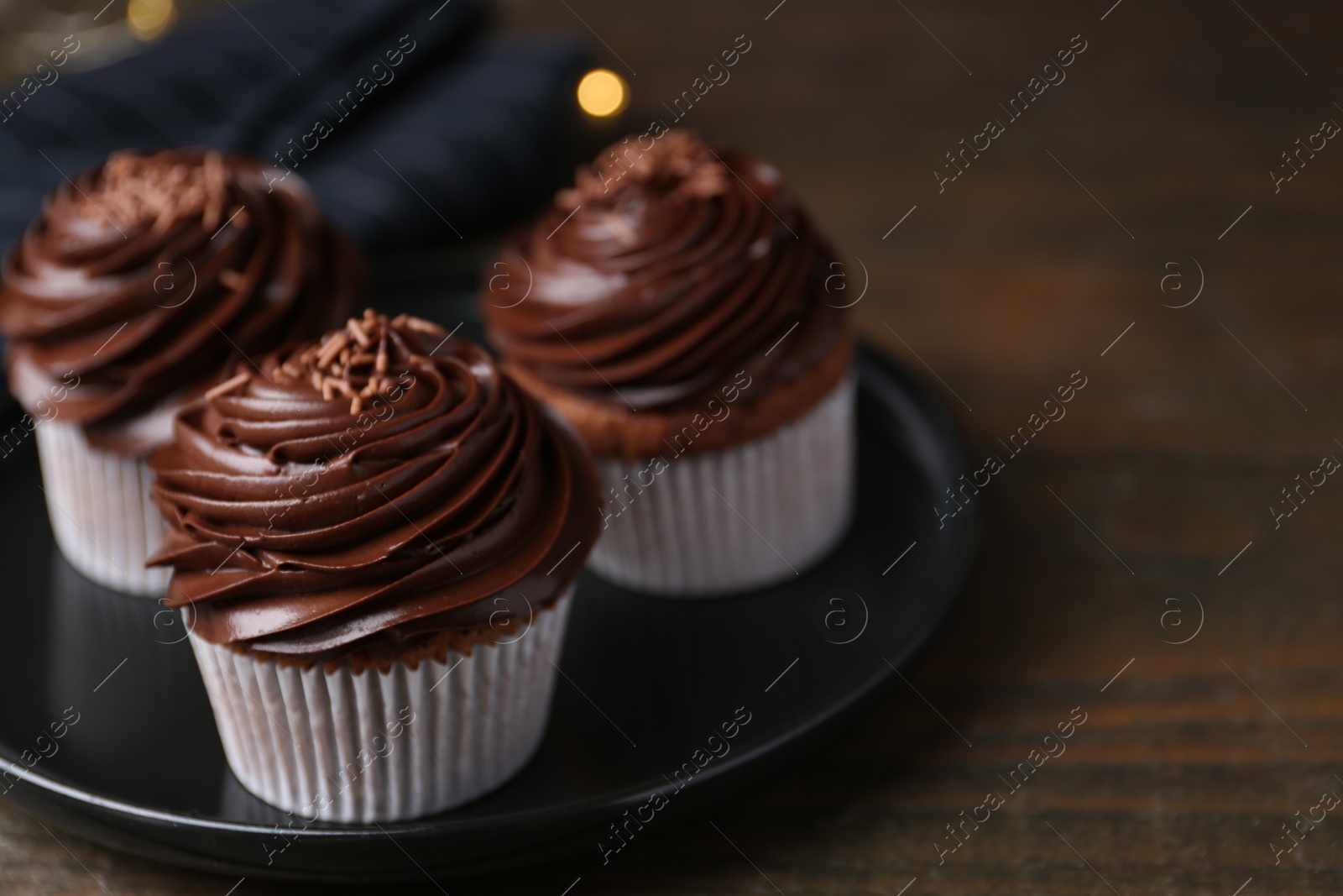 Photo of Tasty cupcakes with chocolate cream on wooden table, closeup. Space for text