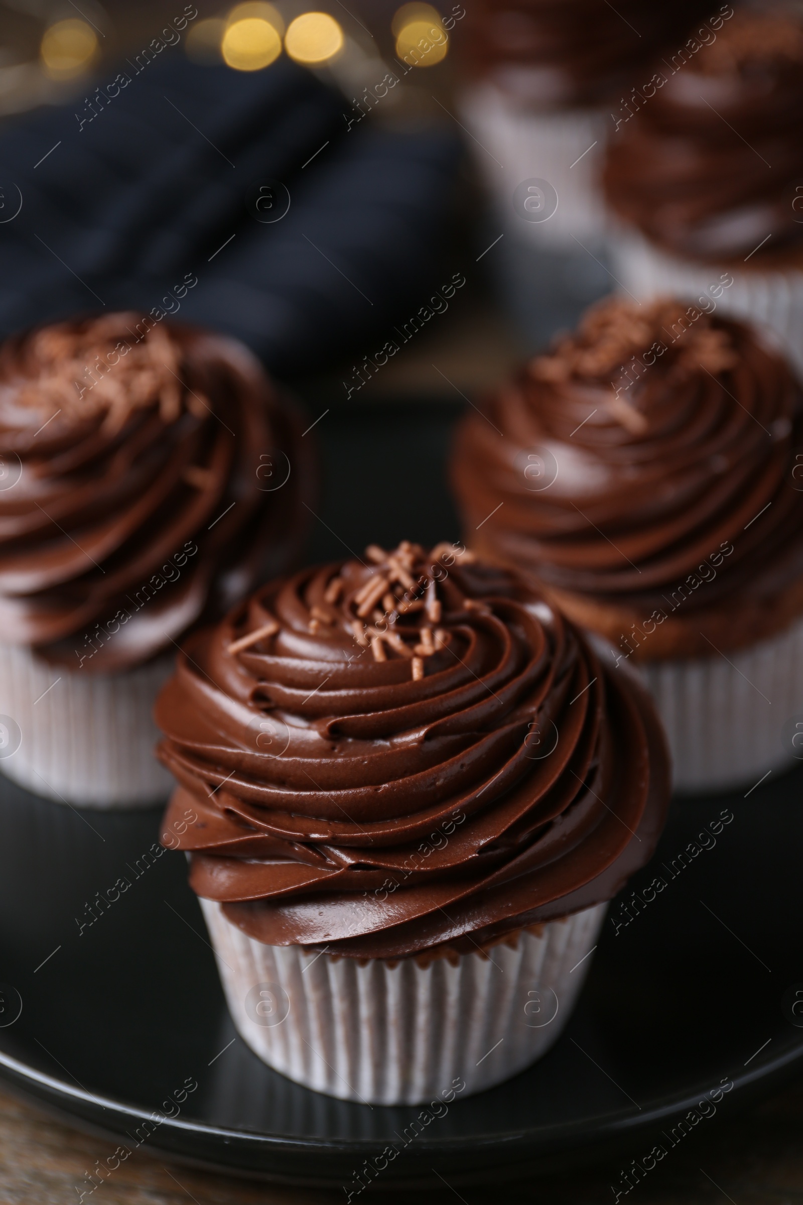 Photo of Tasty cupcakes with chocolate cream on wooden table, closeup