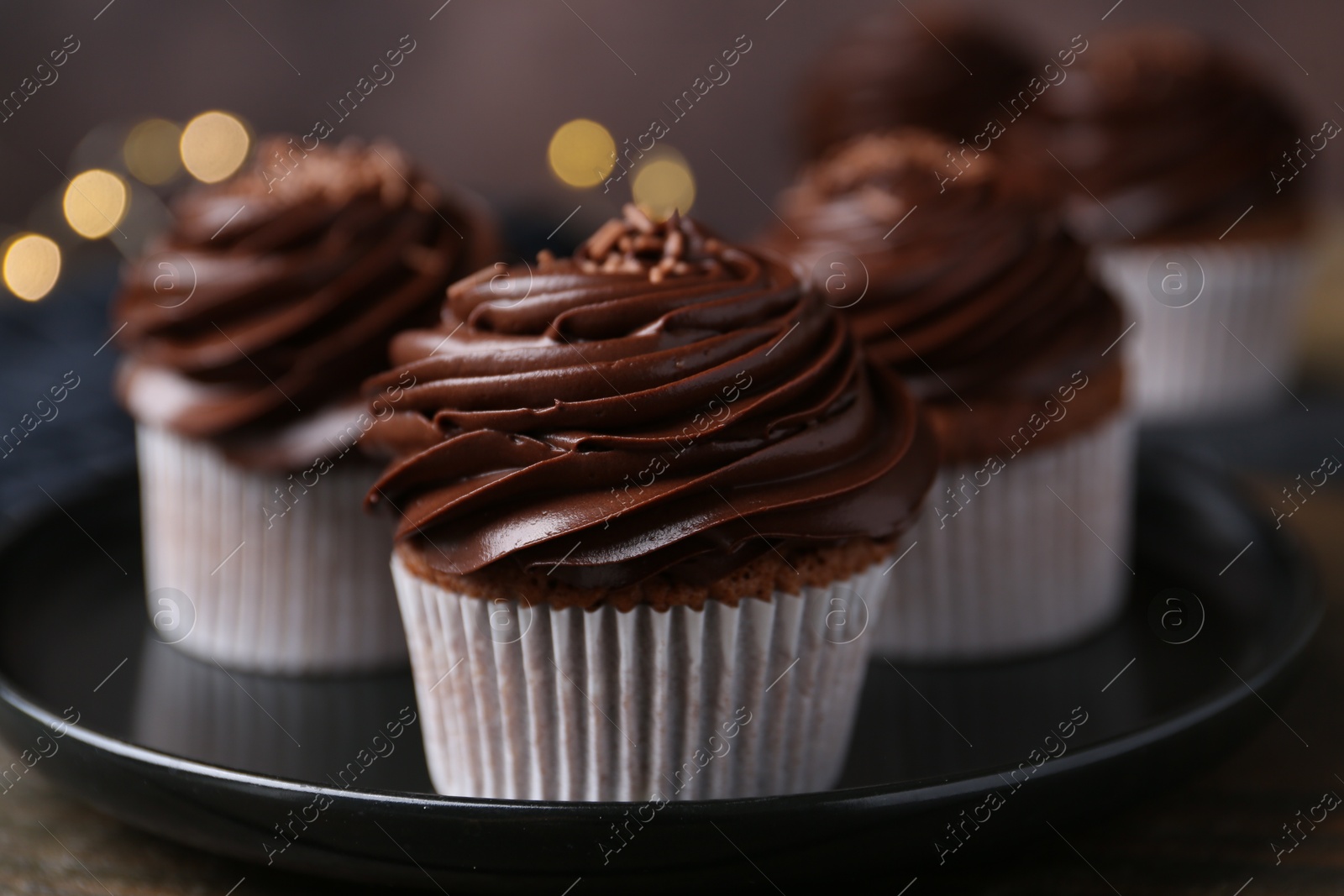 Photo of Tasty cupcakes with chocolate cream on wooden table, closeup