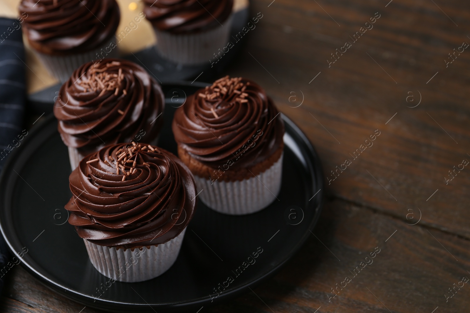 Photo of Tasty cupcakes with chocolate cream on wooden table, space for text