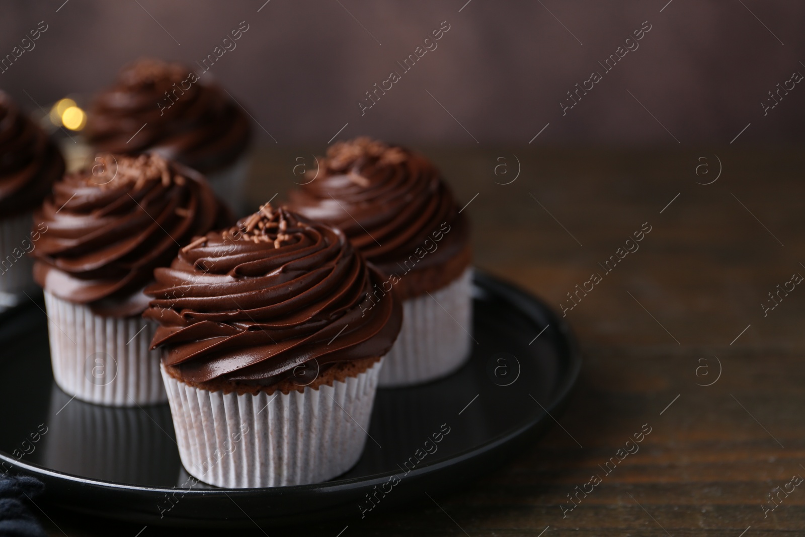 Photo of Tasty cupcakes with chocolate cream on wooden table, closeup. Space for text