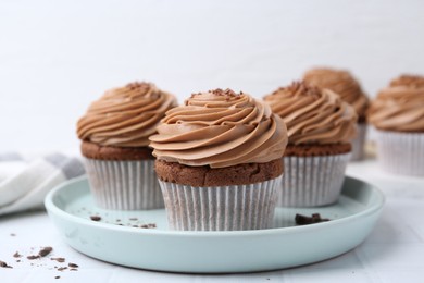 Photo of Tasty cupcakes with chocolate cream on white tiled table