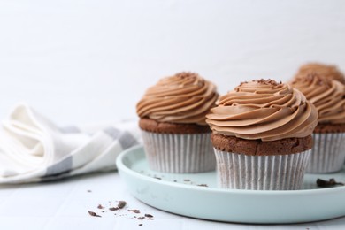 Photo of Tasty cupcakes with chocolate cream on white tiled table, closeup. Space for text