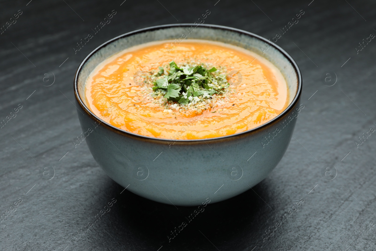 Photo of Delicious sweet potato soup with parsley and parmesan cheese in bowl on grey textured table, closeup