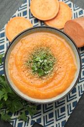 Photo of Delicious sweet potato soup with parmesan cheese in bowl and fresh ingredients on grey table, flat lay