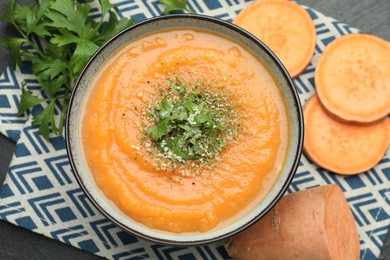 Photo of Delicious sweet potato soup with parmesan cheese in bowl and fresh ingredients on grey table, flat lay