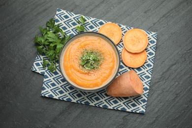 Photo of Delicious sweet potato soup with parmesan cheese in bowl and fresh ingredients on grey textured table, flat lay