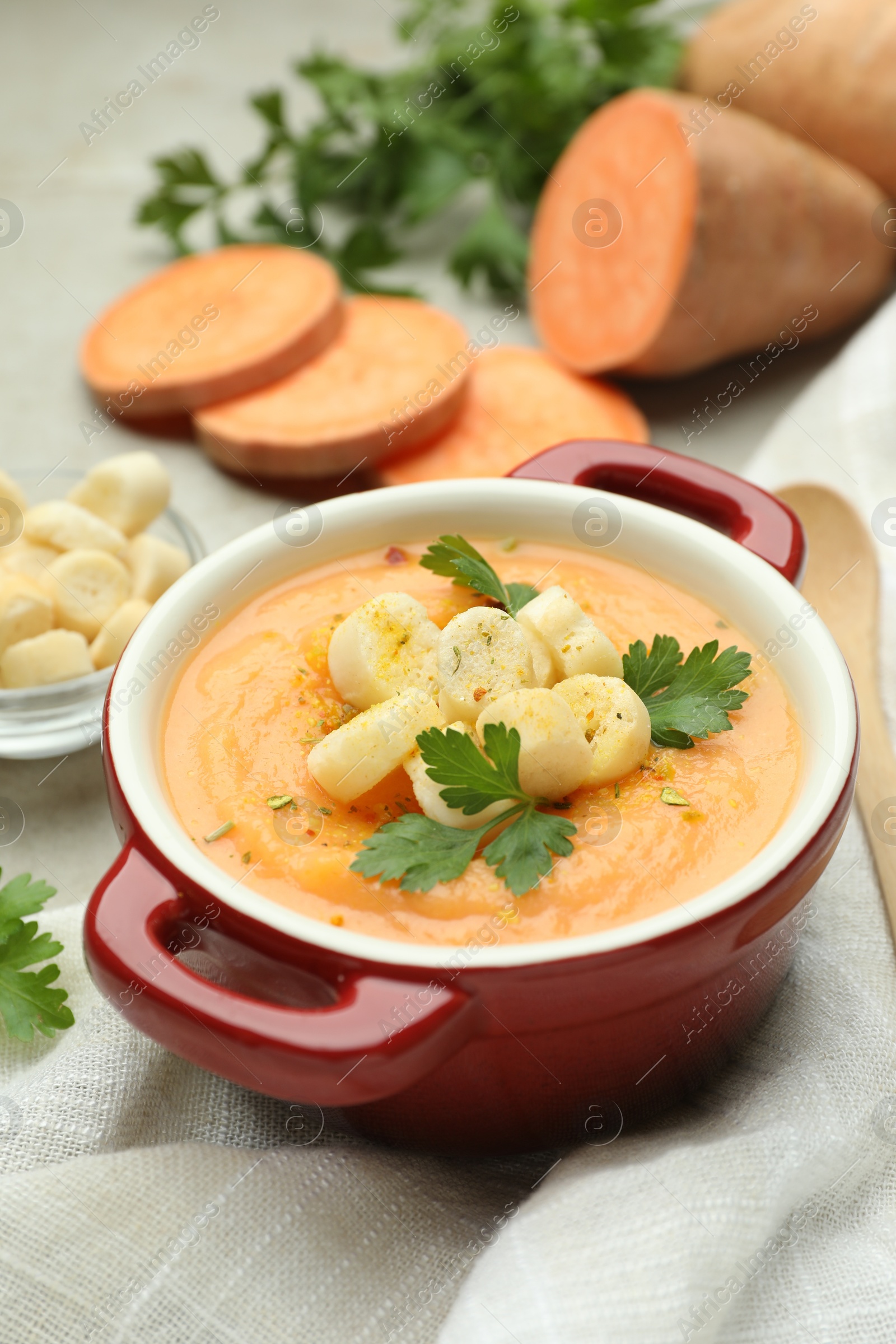 Delicious sweet potato soup with croutons and parsley on light table, closeup Photo of Delicious sweet potato soup with croutons and parsley on light table, closeup
