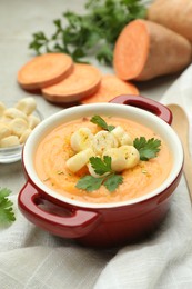 Photo of Delicious sweet potato soup with croutons and parsley on light table, closeup