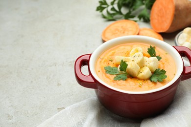 Photo of Delicious sweet potato soup with croutons and parsley on light textured table, space for text