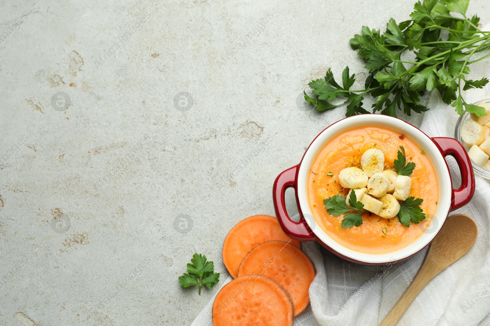 Photo of Delicious sweet potato soup with croutons and fresh ingredients on light textured table, flat lay. Space for text