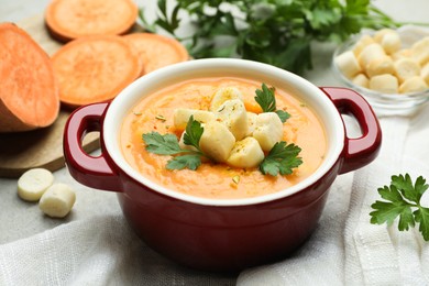 Photo of Delicious sweet potato soup with croutons and parsley on light table, closeup