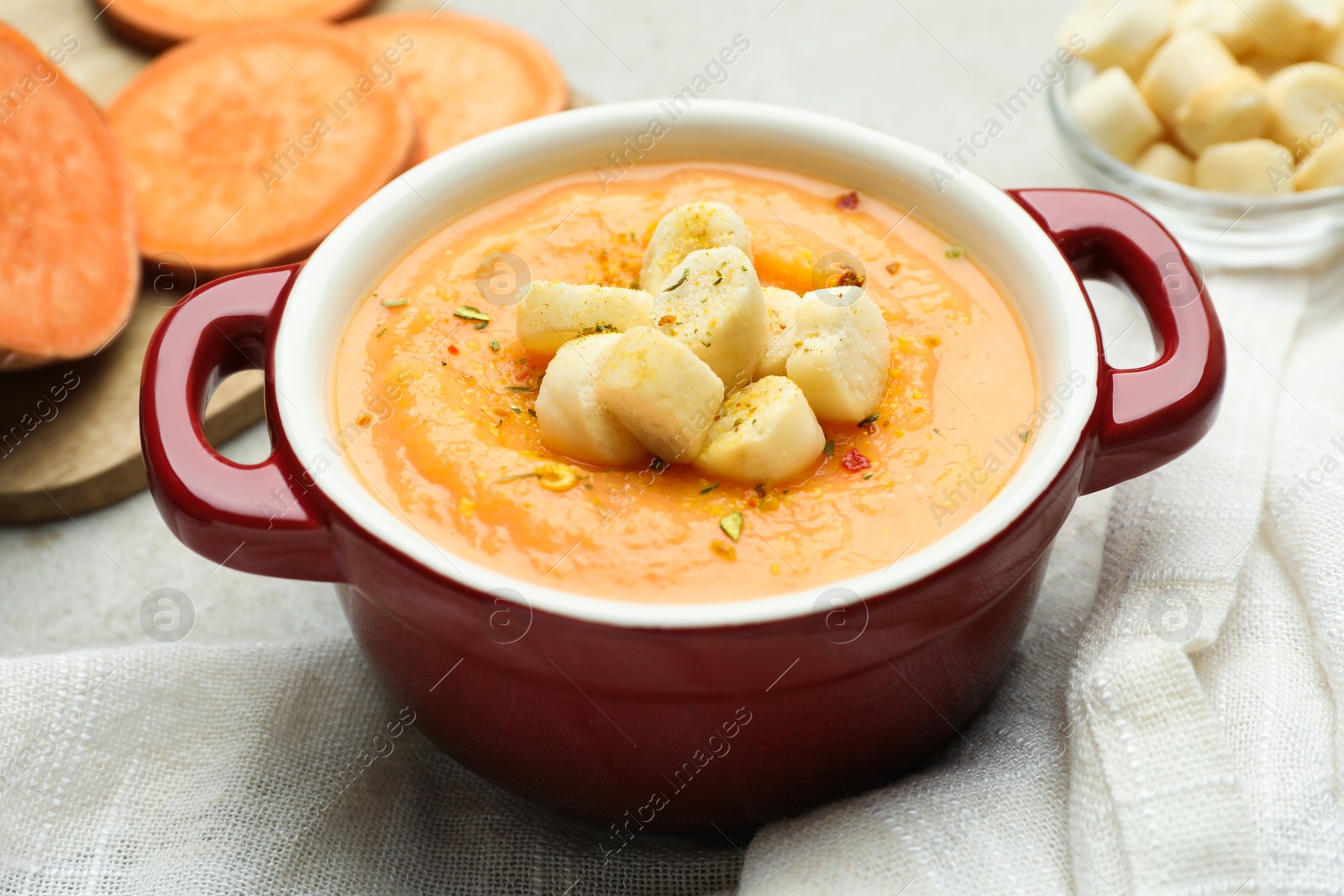 Photo of Delicious sweet potato soup with croutons on light table, closeup