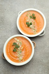 Photo of Delicious sweet potato soup with pumpkin seeds and parsley in bowls on grey textured table, top view