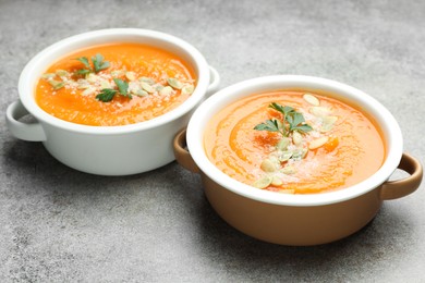 Photo of Delicious sweet potato soup with pumpkin seeds and parsley in bowls on grey textured table, closeup