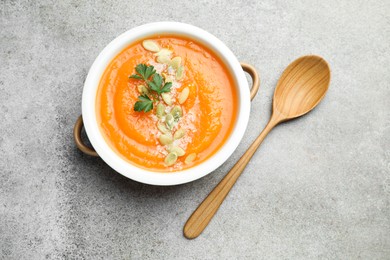 Photo of Delicious sweet potato soup with pumpkin seeds and parsley in bowl served on grey textured table, top view