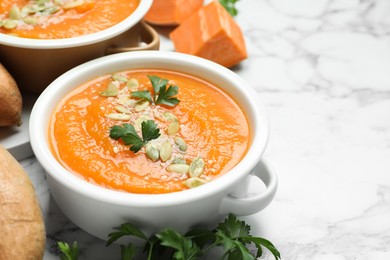 Photo of Delicious sweet potato soup with fresh ingredients on white marble table, closeup. Space for text