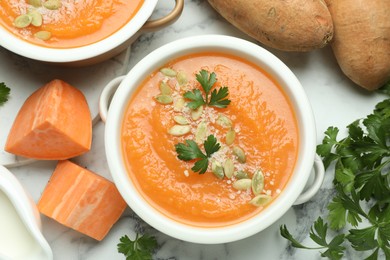 Photo of Delicious sweet potato soup with fresh ingredients on white marble table, flat lay