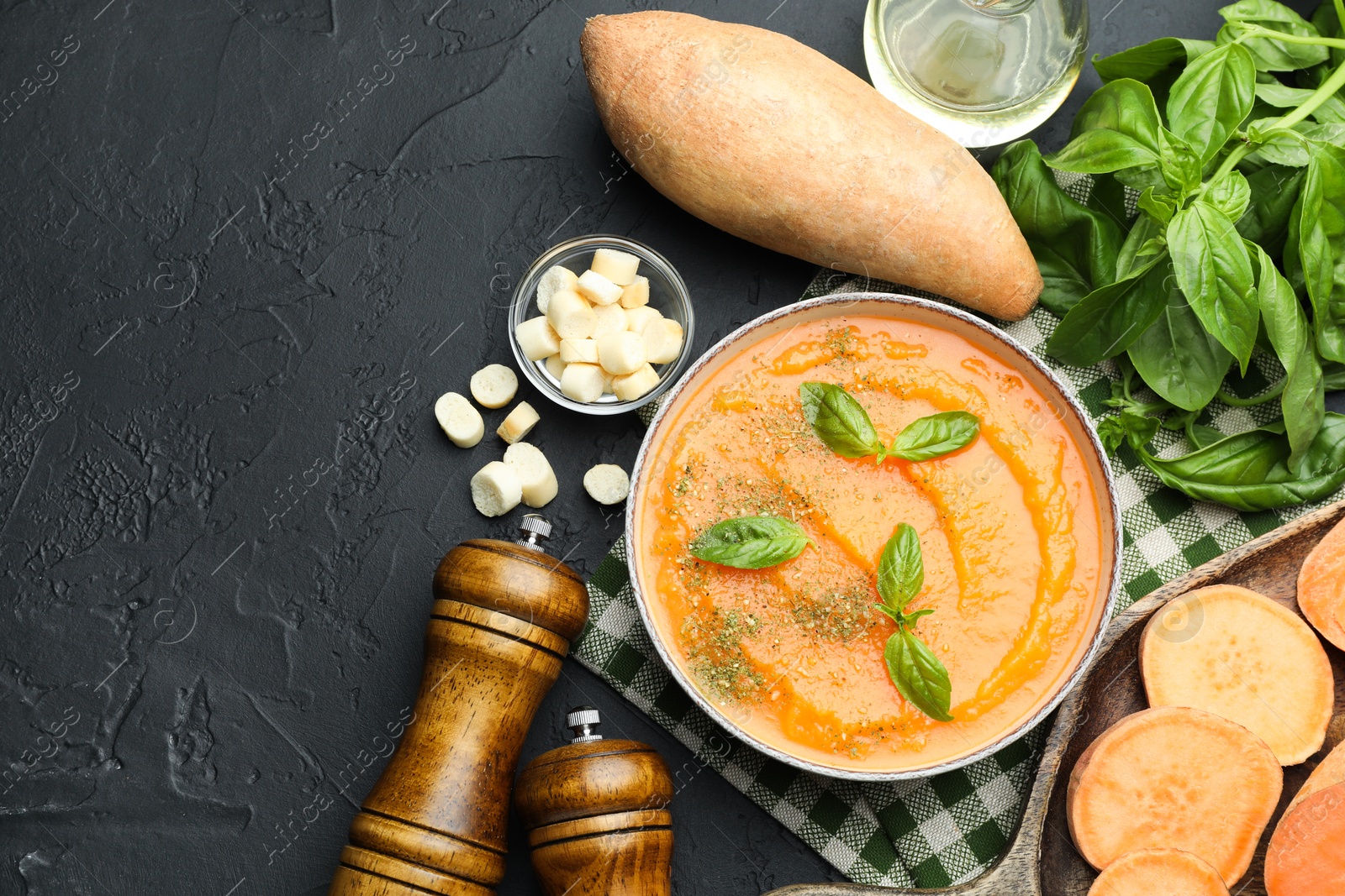 Delicious sweet potato soup in bowl with croutons and fresh ingredients on grey textured table, flat lay Photo of Delicious sweet potato soup in bowl with croutons and fresh ingredients on grey textured table, flat lay