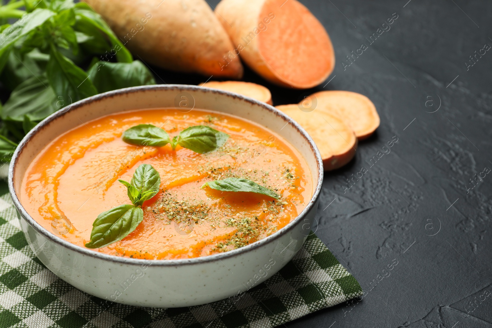 Delicious sweet potato soup in bowl and fresh ingredients on grey textured table, closeup Photo of Delicious sweet potato soup in bowl and fresh ingredients on grey textured table, closeup
