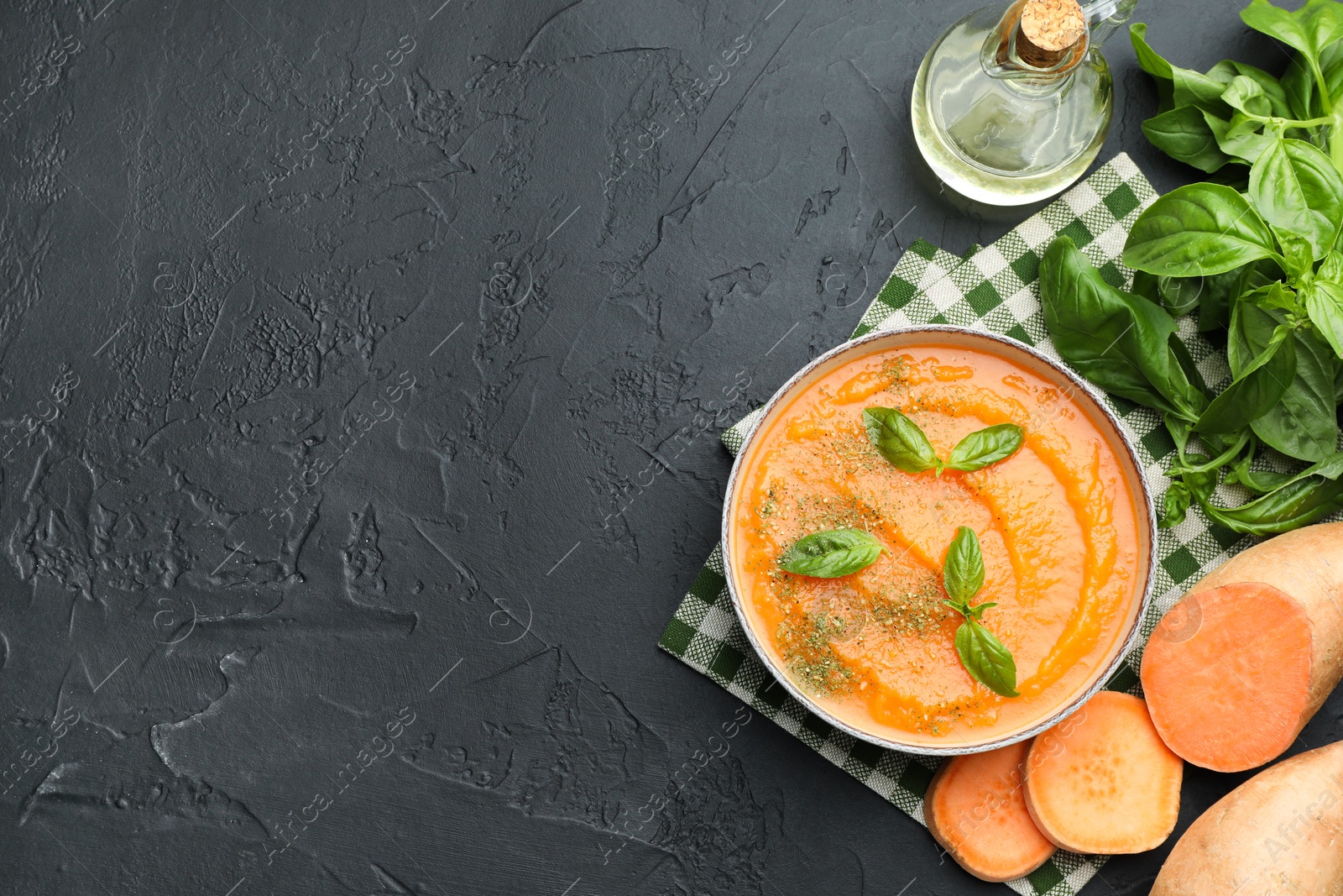 Delicious sweet potato soup in bowl with fresh ingredients on grey textured table, flat lay. Space for text Photo of Delicious sweet potato soup in bowl with fresh ingredients on grey textured table, flat lay. Space for text