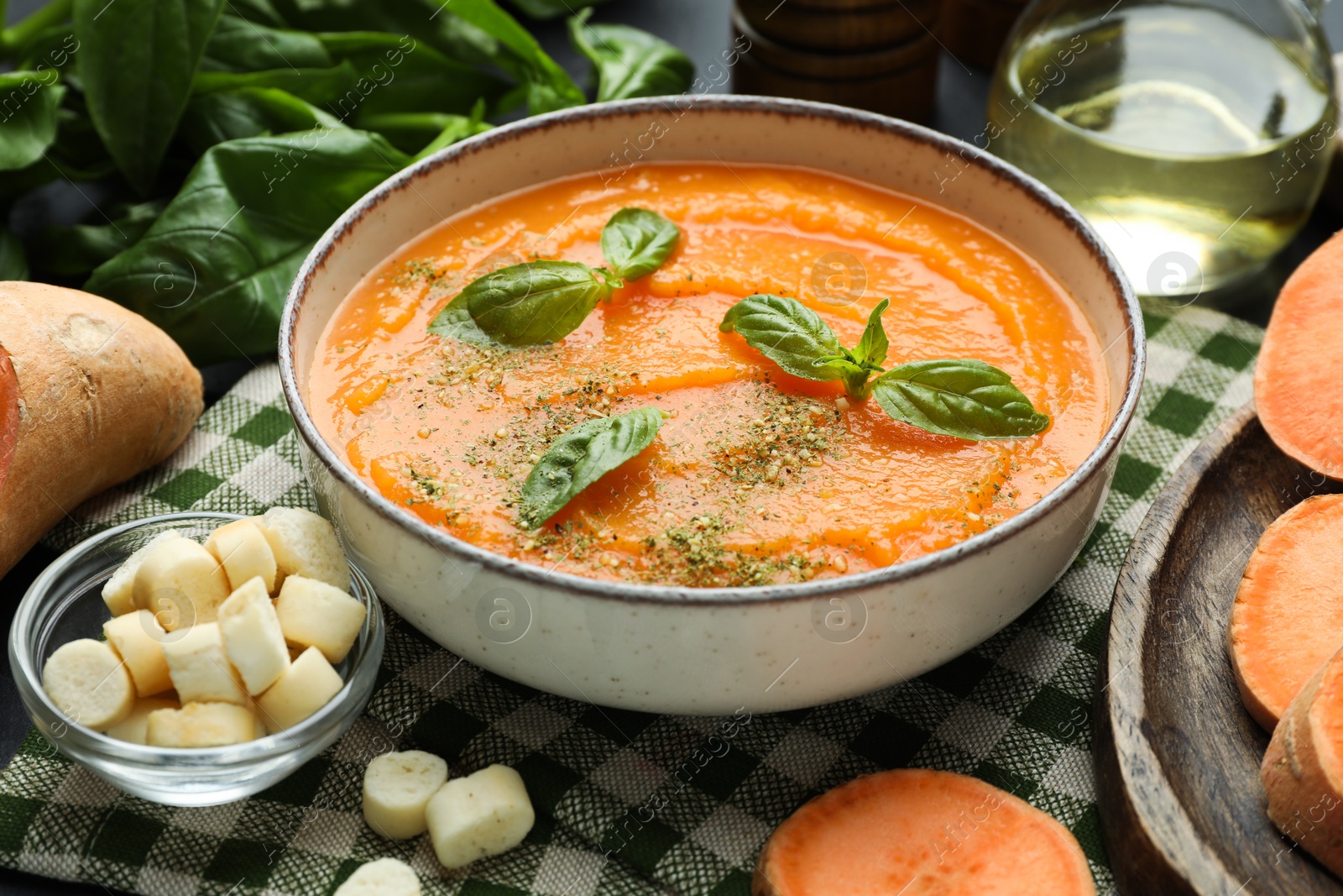 Photo of Delicious sweet potato soup in bowl served on grey table, closeup