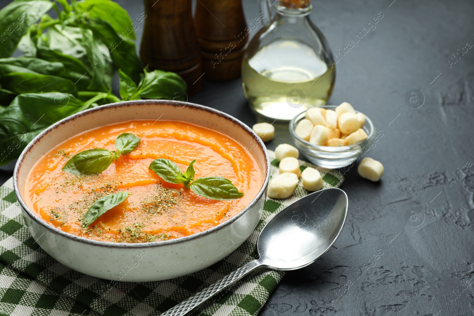 Photo of Delicious sweet potato soup in bowl served on grey textured table, closeup