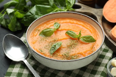 Photo of Delicious sweet potato soup in bowl served on grey table, closeup